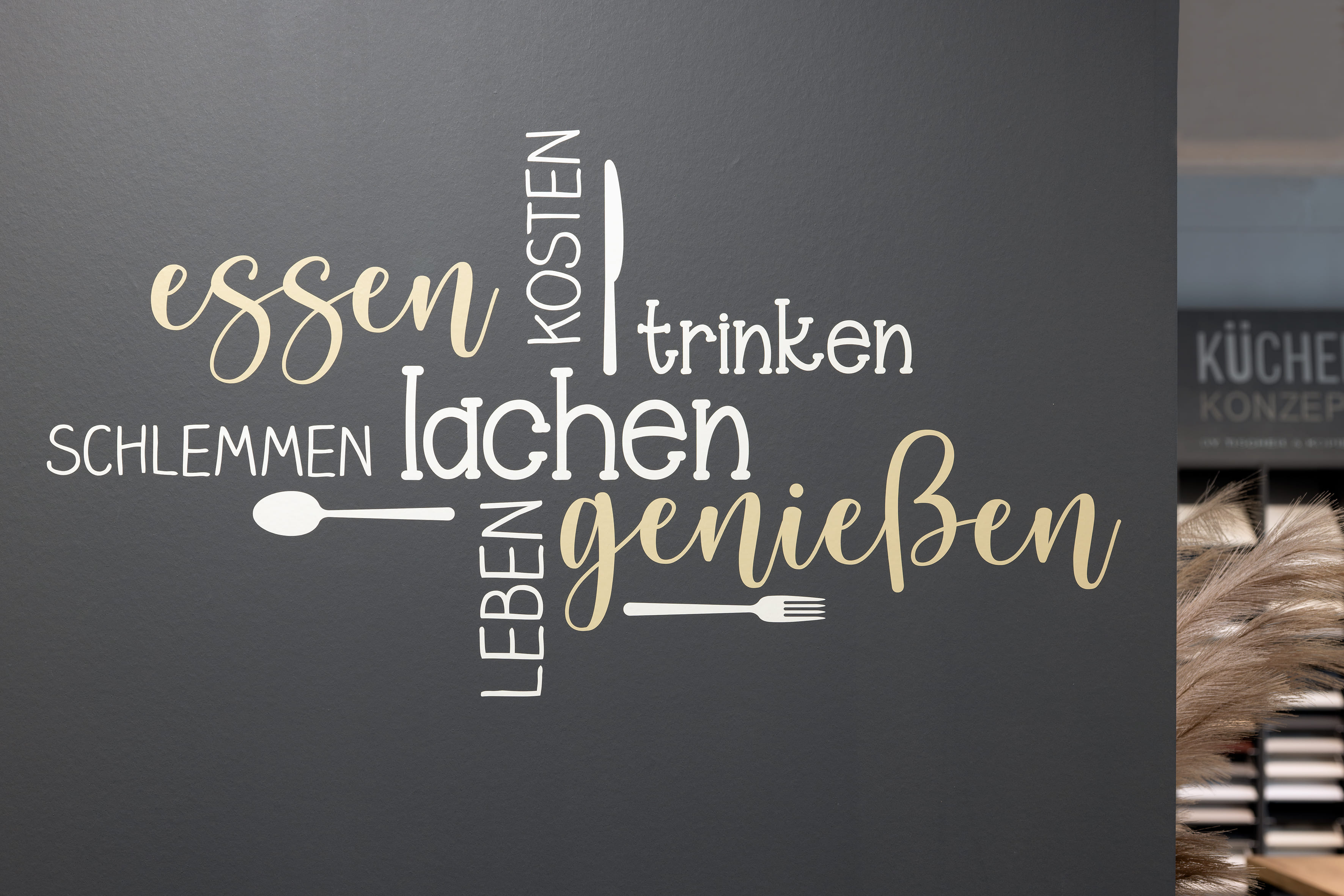 Wand mit Schriftzug: essen, lachen, genießen, trinken, schlemmen, kosten, leben