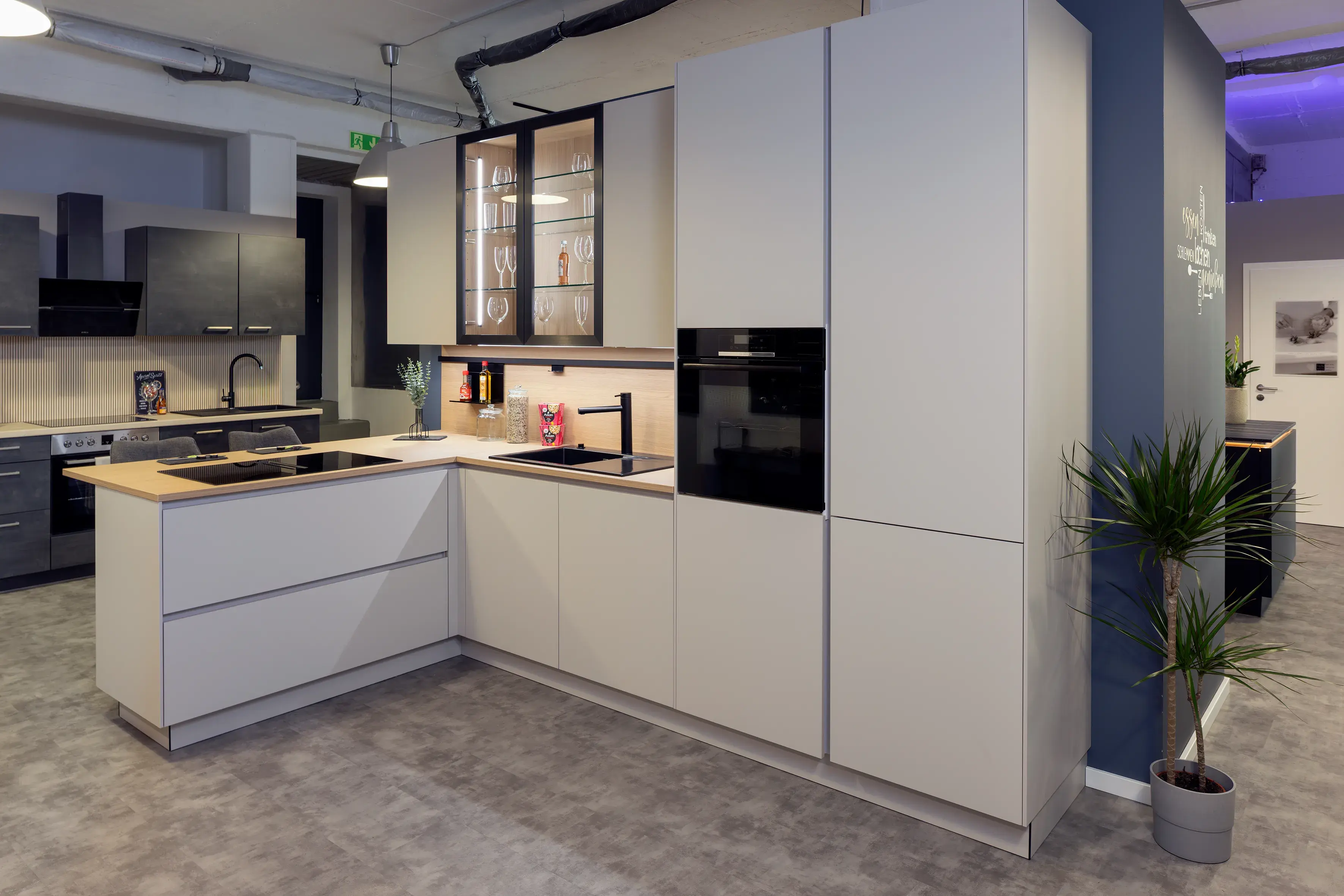 Moderne Einbauküche mit hellen Fronten, Holzarbeitsplatte und Glasvitrine.