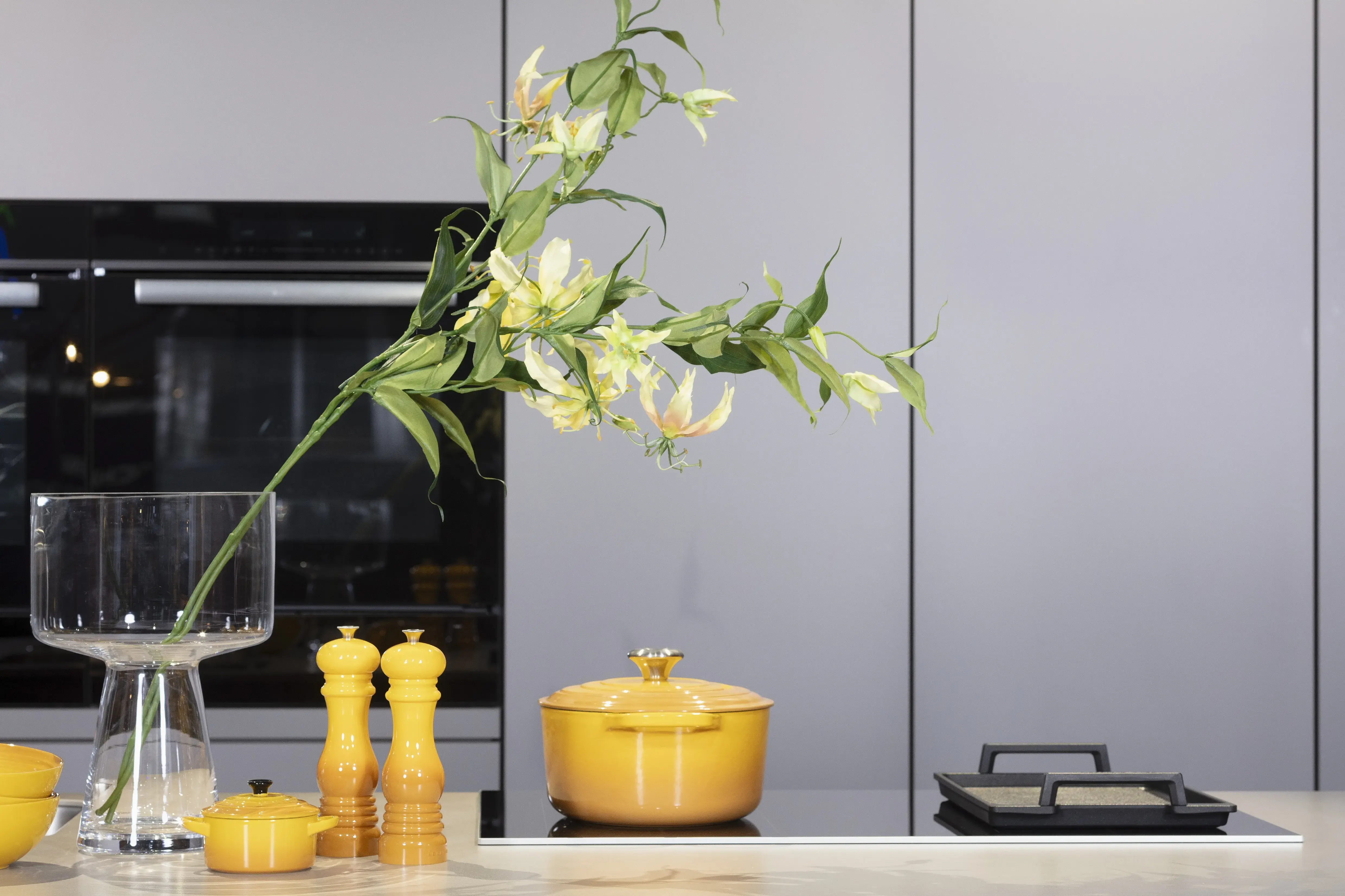 Concept130ART Front: SMART-GL Sandgrau metallic APL: SMART-GL Carbon metallic Geräte Blaupunkt Armatur und Spüle: Franke  Features: Insellösung mit Thekenfunktion mit Schubladen, Teppanyakiaufsatz für Kochfeld, Schubladen in Silber, Schubladen mit Griffmulde, Nischenlösung in Blau mit Regalfunktion.